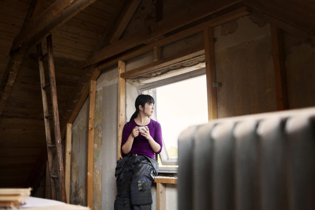 After understanding builders risk in Canada, a woman leans against a window in her attic