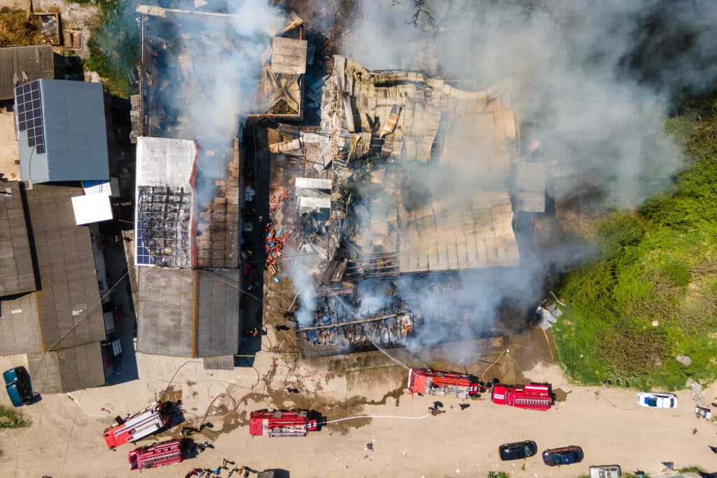Aerial view of firefighters extinguishing ruined building on fir