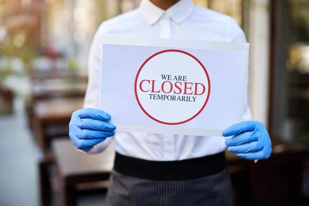 Close up of cafe owner holding closed sign due to COVID pandemic